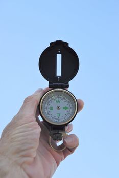 A black lensatic compass and light blue sky