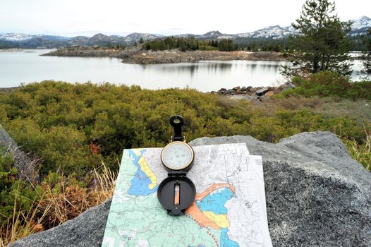 A hiking map and compass overlooking a lake in the California sierra nevada mountains.