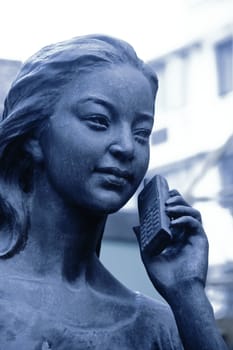 bronze statue talking at the mobile phone 