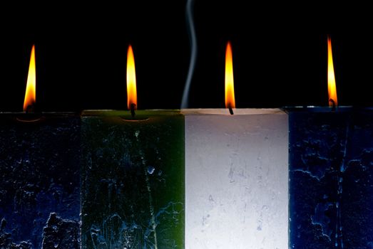 Four burning candles in a dark room