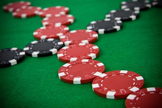 Crossed lines of red and black poker chips on green poker table.