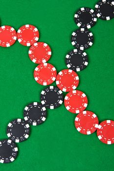 Crossed lines of red and black poker chips on green poker table. Top view.