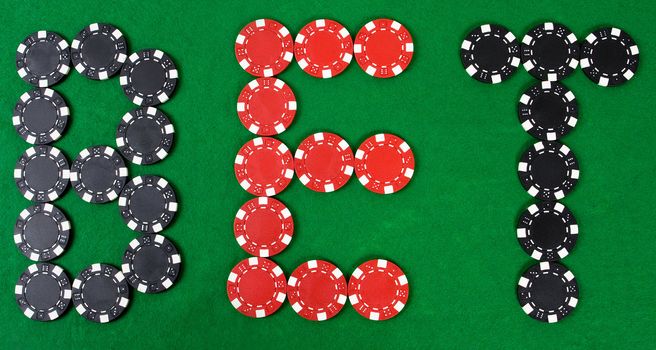 Bet - word build using red and black poker chips. Green poker table.