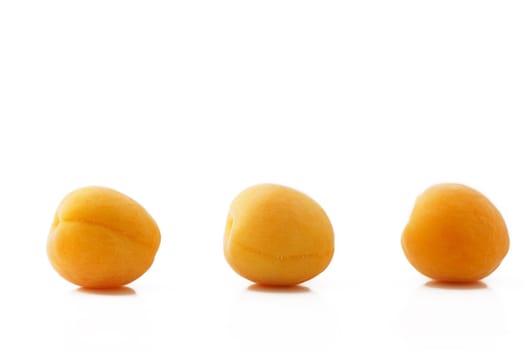 three apricots in a row on white background