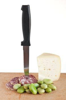 cutting board with salami pecorino broad beans and knife isolated on white background with clipping path