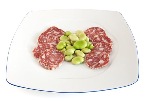 broad beans and salami sliced on a white plate isolated with clipping path