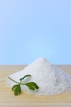 Sea salt and parsley on top of a wood table.
