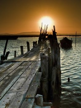Picturesque landscape of a sunset on a coastal scene with a boat on a pier.