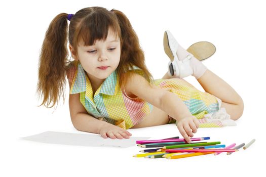 A little girl draws with crayons on a white background