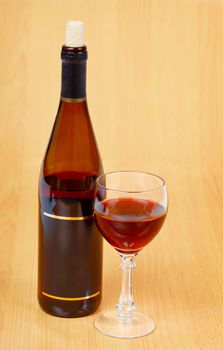 A bottle of red wine and a glass on a wooden table