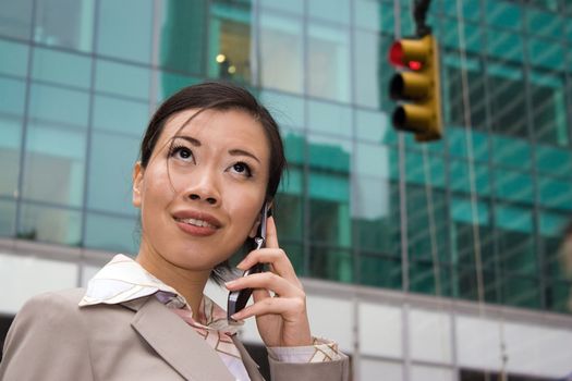 An attractive Asian business woman talking on her cell phone in the city.