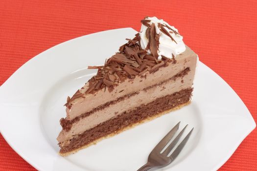 Piece of chocolate cake on a plate with red background