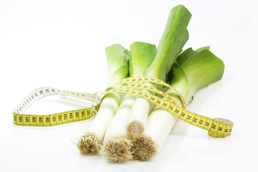 Fresh leek with measuring tape on bright background