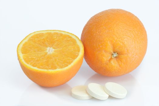 Large pills with orange fruits tube on bright background
