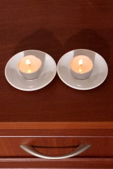 Two candles on a locker and the drawer handle form a smiling face