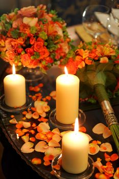 Close up of table decorated with burning candles and flower petals, romantic scene.