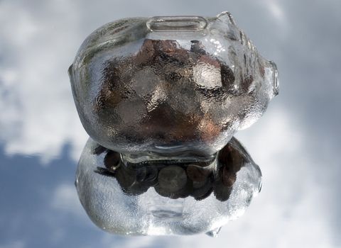 glass piggy bank floating in the sky with a reflection in the clouds