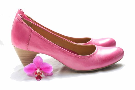 A pair of pink leather ladies shoes and a pink orchid