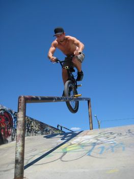 A young caucasian male BMX bike rider doing a trick down a hand-rail at a skatepark in British Columbia, Canada