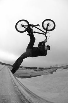 A young caucasian male doing a trick on a ramp at a skatepark with his bmx bike