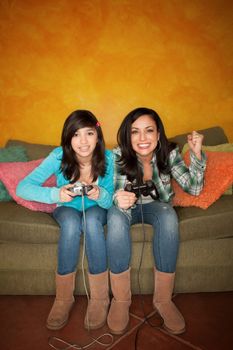 Attractive Hispanic Woman and Girl Playing a Video Game with Handheld Controllers