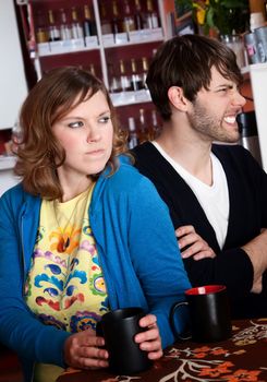 Bickering and frustrated couple sitting with coffee at a table