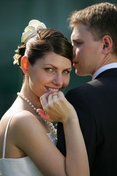 Close up of smiling bride on wedding day leaning on shoulder of new husband.