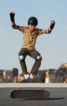 Boy jumping from skateboard wearing protective gear