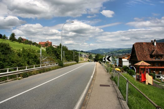 Summer landscape of rural road in Switzerland. Swiss hilly countryside.