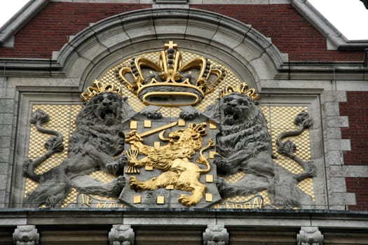 Coat of arms of Kingdom of Netherlands, Europe. Facade of Amsterdam Railway Station.