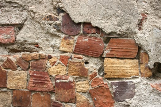 Scruffy wall made of random brick pieces. Urban decay, building falling apart. Background texture.