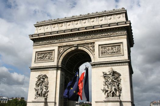 Famous landmark of Paris, France. Arc de Triomphe (Arch of Triumph) located at Place Charles de Gaulle. Flags of EU and France.