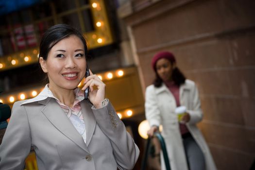 An attractive Asian business woman talking on her cell phone in the city.