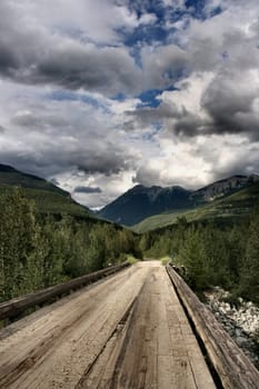 Wooden bridge and beautiful mountain landscape of Rocky Mountains in Canada. Near Kinbasket lake.