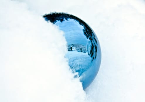 This image shows a half snowcapped blue crystal ball with reflection