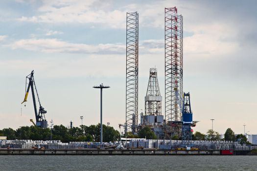 Industrial cranes and drilling platform in dock at the riverside