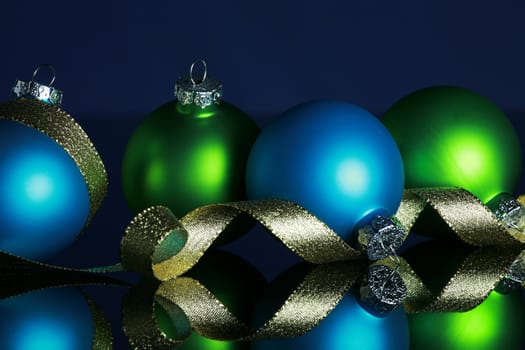 Christmas ornaments and gold ribbon on dark blue background, focus ob blue ball and ribbon