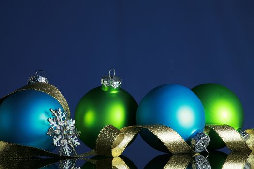 Christmas ornaments and gold ribbon on dark blue background, focus ob blue ball and ribbon