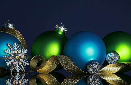 Christmas ornaments and gold ribbon on dark blue background, focus ob blue ball and ribbon