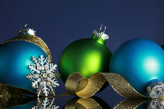 Christmas ornaments and gold ribbon on dark blue background, focus ob blue ball and ribbon