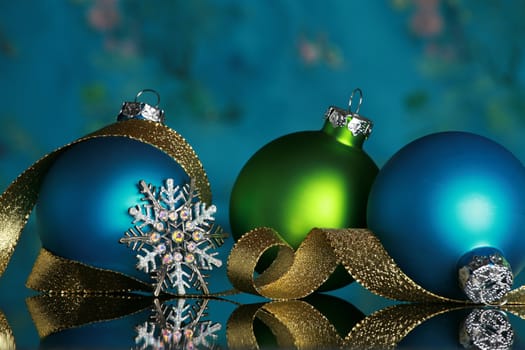Christmas ornaments and snowflake on reflective surface, focus on snowflake