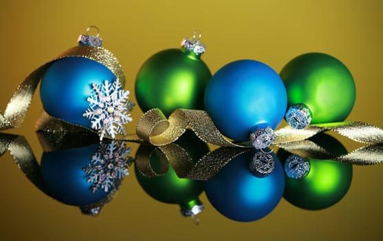 Christmas ornaments on yellow background, focus on blue ball