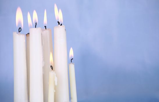 Candles burning against soft blue background