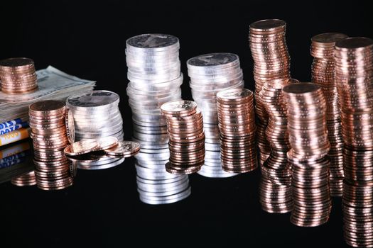 Stacks of silver and gold coins on black reflective surface