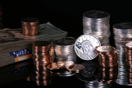 Stacks of silver and gold coins on black reflective surface