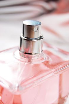 detail of pink bottle of perfume on metalic back