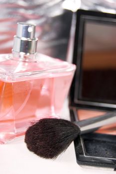 Brush, powder and pink bottle of parfum