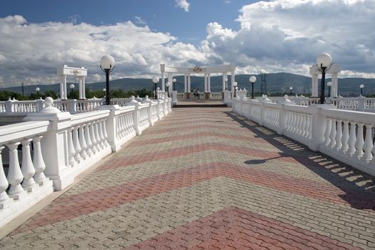 Balcony with white columns on a background of the sky with clouds.