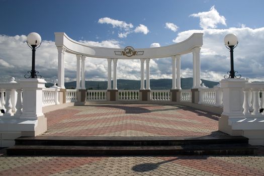 Balcony with white columns on a background of the sky with clouds.