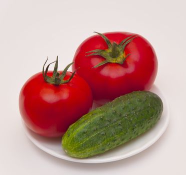 Ripe juicy vegetables cucumber with tomato on white background